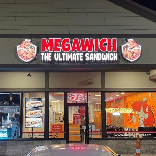 Exterior of Megawich restaurant at night, with a bright red and white sign and illuminated windows.